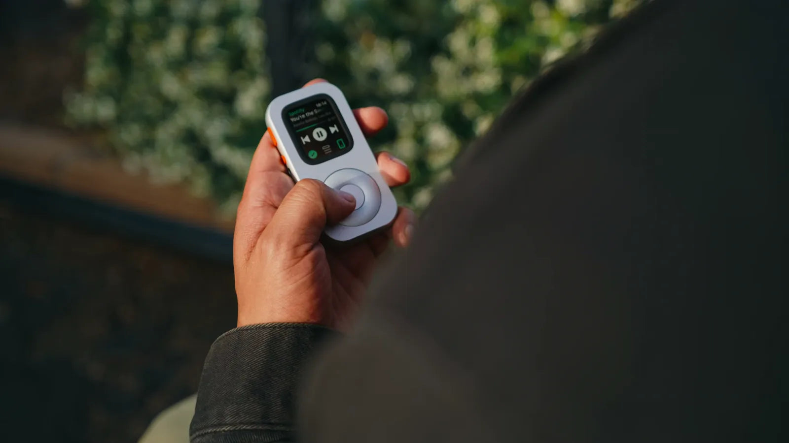 Front view of RePod in hand with Spotify playback controls on Apple Watch
