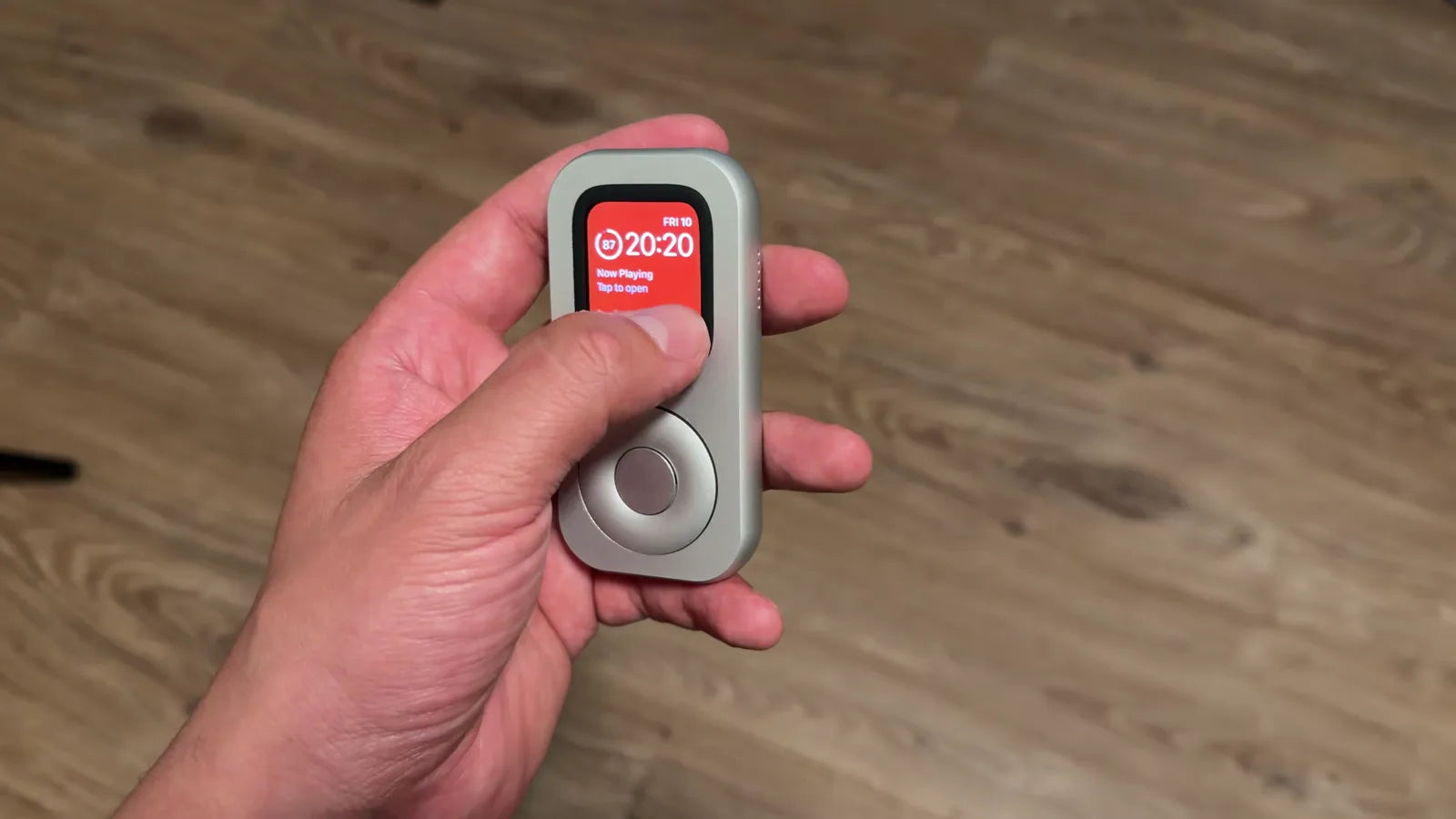 Close front view of RePod in hand with the Apple Watch display visible