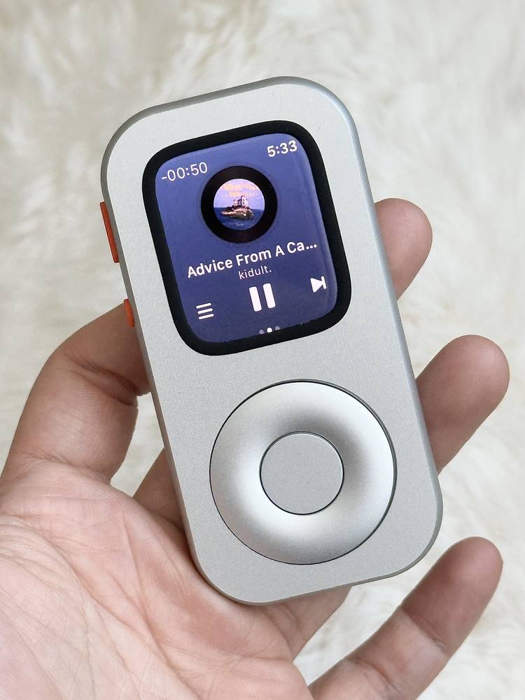 Close front view of RePod in a hand with music playback visible on Apple Watch